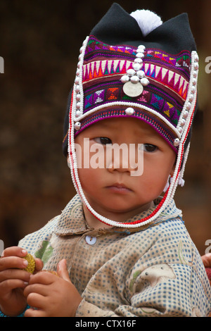 Ein Babymädchen des AKHA-Stammes trägt ein Childs Headdresse gemacht von Perlen, Silber und hand ragte Baumwolle - KENGTUNG, MYANMAR Stockfoto