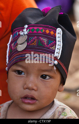 Ein Babymädchen des AKHA-Stammes trägt eine Kinder-Headdresse, Perlen, Silber und Baumwolle - Dorf in der Nähe von KENGTUNG, MYANMAR Stockfoto