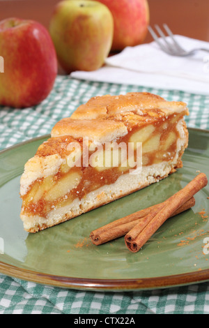 Ein Stück Apfelkuchen mit Gitter Teig Kruste. Dekoriert mit Zimtstangen und frische Äpfel. Stockfoto