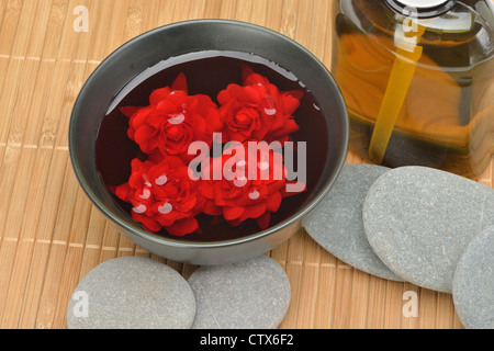 Objekt für den Wellnessbereich. Kiesel, Lily, Flüssigseife, Schale mit Rosen im Wasser. Stockfoto