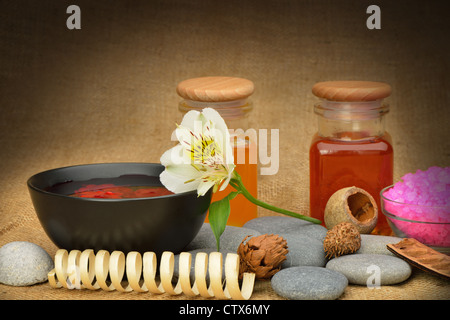 Objekt für den Wellnessbereich. Kerzen brennen, Kiesel, eine Lilie, eine Flasche mit Öl, Schale mit den Blütenblättern von Rosen in Wasser, und ein anderes. Stockfoto
