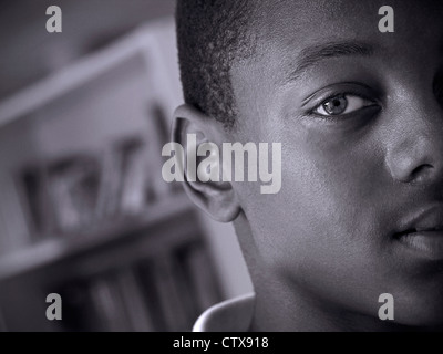 Afro Karibik Teenager schwarzen männlichen Studenten Schüler enge halbe Gesicht kraftvolles Porträt in Schulbibliothek B&W Stockfoto