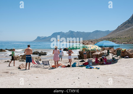 Urlauber, die zum Sonnenbaden am Strand von Rooi Els auf der Cape Whale Coast in der Nähe von Gordons Bay, Western Cape Südafrika Stockfoto