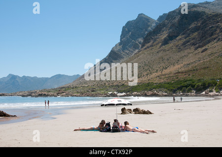 Urlauber, die zum Sonnenbaden am Strand von Rooi Els auf der Cape Whale Coast in der Nähe von Gordons Bay, Western Cape Südafrika Stockfoto