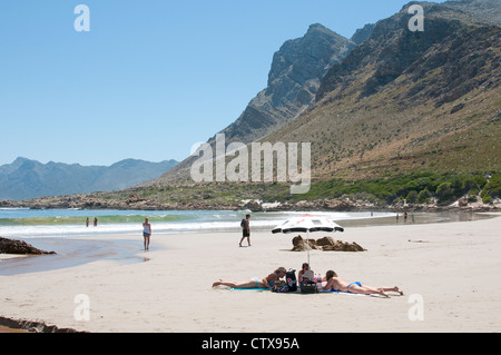 Urlauber, die zum Sonnenbaden am Strand von Rooi Els auf der Cape Whale Coast in der Nähe von Gordons Bay, Western Cape Südafrika Stockfoto