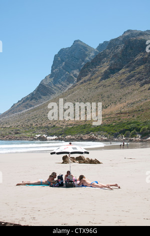 Urlauber, die zum Sonnenbaden am Strand von Rooi Els auf der Cape Whale Coast in der Nähe von Gordons Bay, Western Cape Südafrika Stockfoto