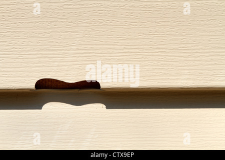 Eine Nahaufnahme eines gebrochenen Beige gefärbt, Vinyl Siding Panel auf ein Haus, das durch Hagel aus einem Hagelsturm beschädigt wurde. Stockfoto