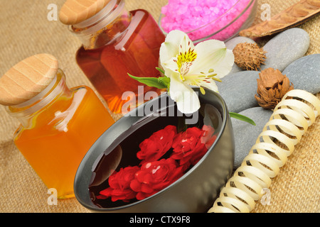 Objekt für den Wellnessbereich. Kerzen brennen, Kiesel, eine Lilie, eine Flasche mit Öl, Schale mit den Blütenblättern von Rosen in Wasser, und ein anderes. Stockfoto