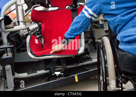 Racer mit Querschnittslähmung im Rollstuhl am Weg Sicherheit Roll Cage Pendeltür Rennwagen Stockfoto