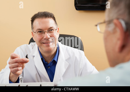 Hörgeräte-Akustiker zeigt ein Hörgerät zu einem Patienten Stockfoto