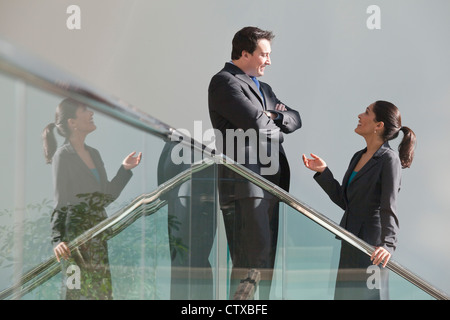 Hispanische Geschäftsfrau im Gespräch mit einem Geschäftsmann auf Treppenhaus im Bürogebäude Stockfoto