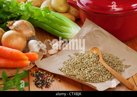 Zutaten für die Herstellung grüner Linsensuppe, angeordnet auf einem alten hölzernen Küchentisch. Stockfoto