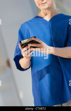 Krankenschwester von SMS-Nachrichten auf ihrem smartphone Stockfoto