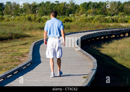 Besucher wandern ein Holzsteg durch Sumpfgebiet in der Nähe von Cameron Prairie National Wildlife Refuge Visitor Center, LA, USA Stockfoto