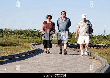 Besucher wandern ein Holzsteg durch Sumpfgebiet in der Nähe von Cameron Prairie National Wildlife Refuge Visitor Center, LA, USA Stockfoto