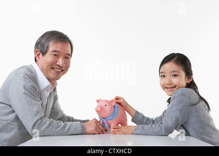 Ein Großvater und Enkelin, die Geld sparen Stockfoto