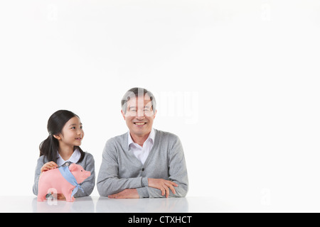 Ein Großvater und Enkelin mit Sparschwein Stockfoto