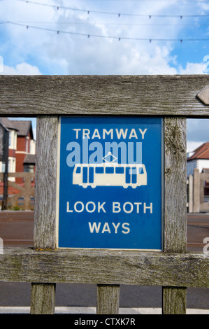 "Straßenbahn. Schauen Sie beide Richtungen. Warnschild durch eine Kreuzung mit der Straßenbahnlinie in Blackpool, Lancashire Stockfoto