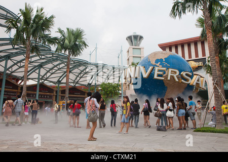 Singapur - März 2012 - Touristen posieren in der Nähe von Universal Studios Logo und Markenzeichen in Sentosa Resorts World, Singapur. Stockfoto