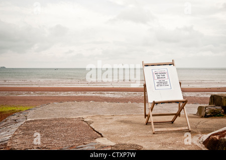 Ein Schild ruht auf einem Liegestuhl am Strand von Paignton Stockfoto