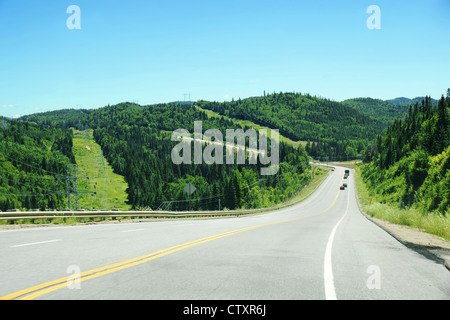 Abschüssigen Straße in borealen Waldpark Hochgebirge mit Powerlines in Bereichen der klare Schnitt, Parc des Laurentides, Quebec, Cana Stockfoto