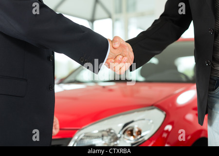 Zwei Männer in Anzügen Händeschütteln nach einem erfolgreichen Autokauf Stockfoto