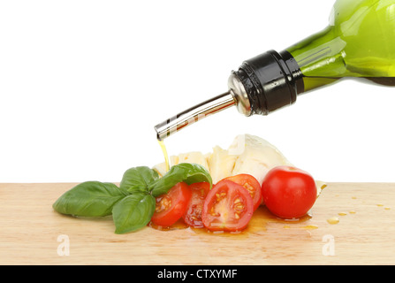 Olivenöl Gießen über Tomaten, Basilikum und Mozzarella auf einem Brett aus Holz Essen Vorbereitung Stockfoto