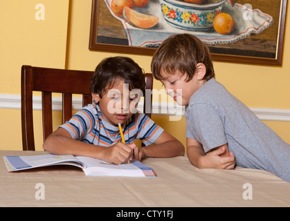 8 Jahre alten mexikanisch-amerikanischen jungen interagiert mit 7 Jahre alten Bruder dabei Hausaufgaben Stockfoto