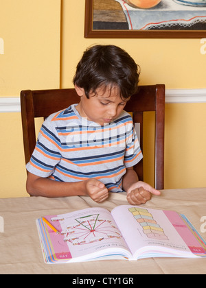 8 Jahre Alter mexikanisch-amerikanischen Grundschule Alter junge benutzt Finger Graf helfen dabei Mathe Schularbeit Hause zu Stockfoto