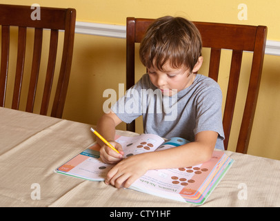 7 Jahre Alter mexikanisch-amerikanischen Grundschule Alter Junge hat Mathe-Hausaufgaben mit Fingern zählen zu Hause Stockfoto