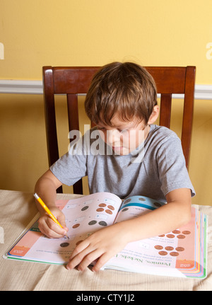 7 Jahre Alter mexikanisch-amerikanischen Grundschule Alter Junge hat Mathe-Hausaufgaben mit Fingern zählen zu Hause Stockfoto