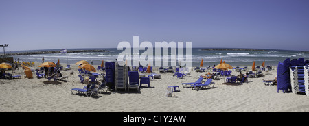 Strandkörbe und Menschen entspannen entlang der Küste in Tel Aviv, Israel Stockfoto