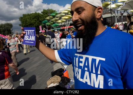 Ein islamischer Aktivist mit dem Team Islam verteilt Karten und Literatur an Passanten in der Plaza außerhalb Stratford Hauptbahnhof, nahe dem Eingang von der Hauptstraße Olympic Park während der Olympiade 2012 in London die 30. Olympiade. Seine Karte liest "erfolgreich sein. Werden Musselin ' und er und seine Gruppe von religiösen Anhänger dürfen ihre Karten zu verteilen und teilen ihren Glauben nur auf einem Teil des Belags von der Polizei genehmigt. Stockfoto