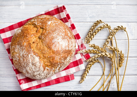 knuspriges Brot mit Weizen auf Holztisch Stockfoto