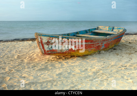 Solo-Ruderboot mit abblätternde Farbe ruht auf Sandstrand in Progreso, Yucatan, Mexiko Stockfoto