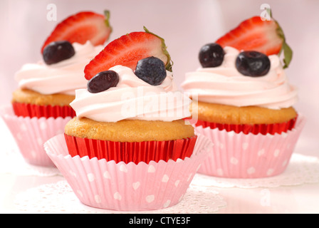 Köstliche Vanille Cupcake mit Erdbeer Glasur und frische Erdbeeren und Heidelbeeren Stockfoto