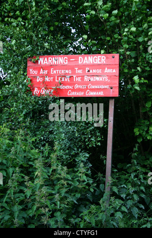 Warnschild Warnung Rot Farbe Board unter den Büschen in den Bergen Wald wo Soldaten Army training live in Irland Wicklow in Europa ist. Stockfoto