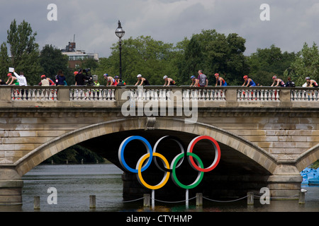 Triathleten Zyklus über Serpentine Brücke im Londoner Hyde Park für den Herren-Triathlon-Wettbewerb während der Olympiade 2012 in London, die 30. Olympiade. Serpentine Brücke markiert die Grenze zwischen dem Hyde Park und Kensington Gardens. Die Triathlon-Konkurrenten rasten über 1,5 km Schwimmen, ein 43km-Rennen und eine 10km run - Team GB Alistair Brownlee, Spaniens Javier Gomez und Jonathan Brownlee (Bruder des Gewinners) errang. (Weitere Beschriftungen in Beschreibung)... Stockfoto