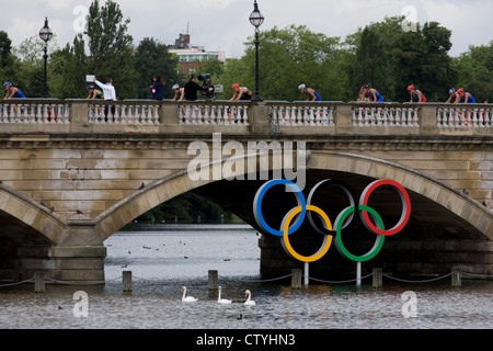 Triathleten Zyklus über Serpentine Brücke im Londoner Hyde Park für den Herren-Triathlon-Wettbewerb während der Olympiade 2012 in London, die 30. Olympiade. Serpentine Brücke markiert die Grenze zwischen dem Hyde Park und Kensington Gardens. Die Triathlon-Konkurrenten rasten über 1,5 km Schwimmen, ein 43km-Rennen und eine 10km run - Team GB Alistair Brownlee, Spaniens Javier Gomez und Jonathan Brownlee (Bruder des Gewinners) errang. (Weitere Beschriftungen in Beschreibung)... Stockfoto