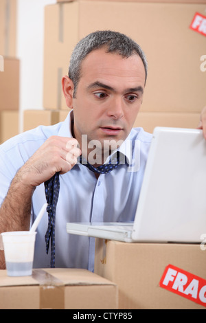 Mann mit einem Laptop, umgeben von Feldern in Panik Stockfoto