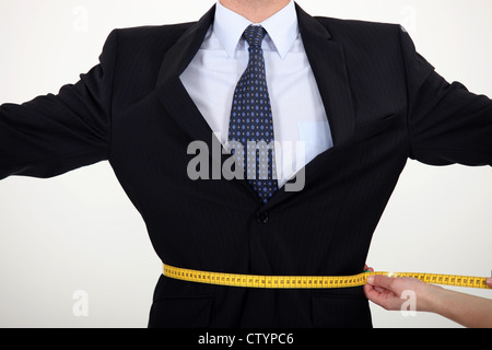 Geschäftsmann mit einem Maßband rund um seine Taille Stockfoto