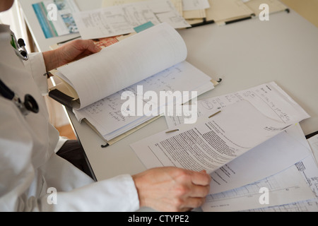 Arzt-sortieren-Out-Papiere auf ihrem Schreibtisch Stockfoto