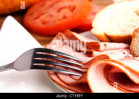 Leckeres Mittagessen mit Schinken, Brot, Käse und Tomaten mit Silber Gabel verteilen. Stockfoto