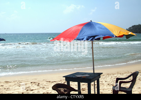 Tisch, Stühle und Sonnenschirm am Strand Stockfoto