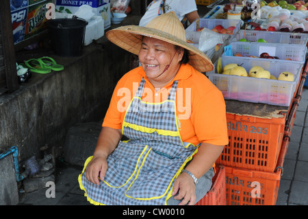 Lächelnde Frau sitzen an ihren überdachten Marktstand, Verkauf von Obst, Asoke Road und Sukhumvit Road, Soi 21, Bangkok Stockfoto