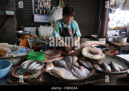 Frau, Reinigung, filetieren von Fisch in überdachten Fisch Marktstand, Asoke Road und Sukhumvit Road, Soi 21, Bangkok. Stockfoto