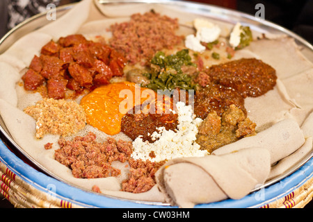 Traditionelle Äthiopische Küche, mehrere Arten von Eintopf und Fleisch auf Injera serviert Stockfoto