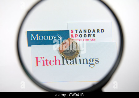 Ein "verletzten", "beschädigt" oder "verwundet" ein-Euro-Münze unter einem Vergrößerungsglas mit den Logos für die drei Rating-Agenturen. Stockfoto