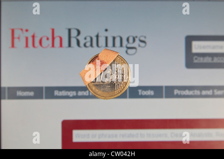 Eine "Verletzte" oder "beschädigt" oder "verwundet" ein-Euro-Münze mit der Fitch Ratings-Kredit-Rating-Agentur-Website hinter. Stockfoto