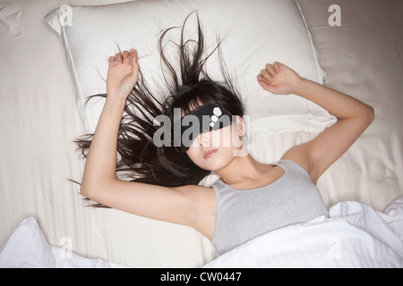 Frau mit Maske im Bett schläft Stockfoto